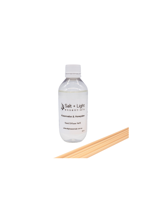 Clear bottle of reed diffuser liquid with reeds lying next to it