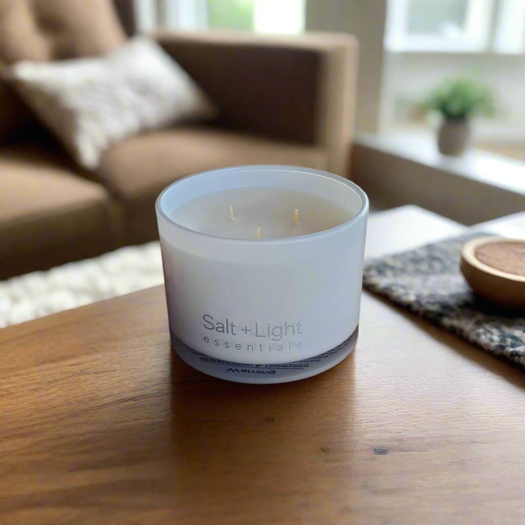 triple wick candle in white glass jar on table